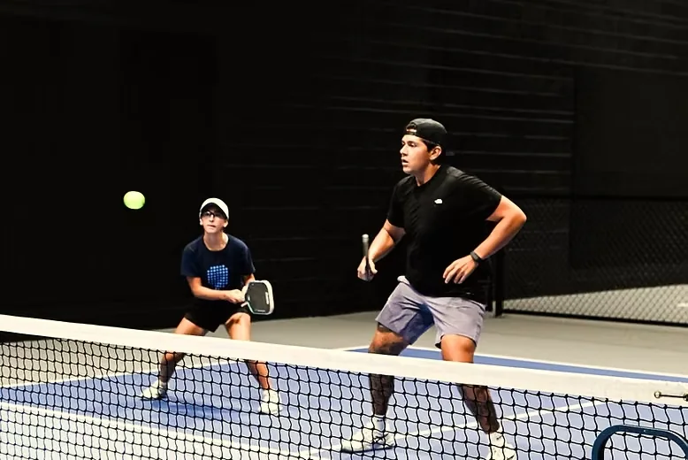 Two players at the net on an indoor court at The Grove